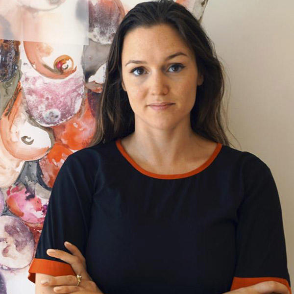 a woman with long dark hair stands in front of an artwork