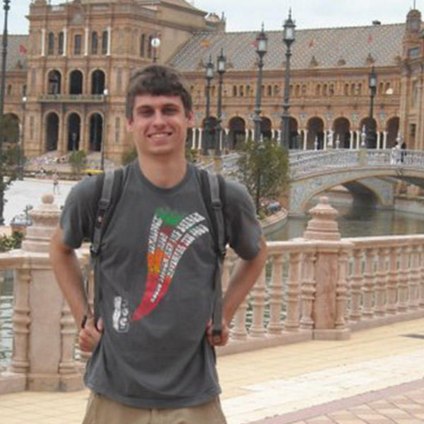 a young man with a backpack in front of a Spanish plaza