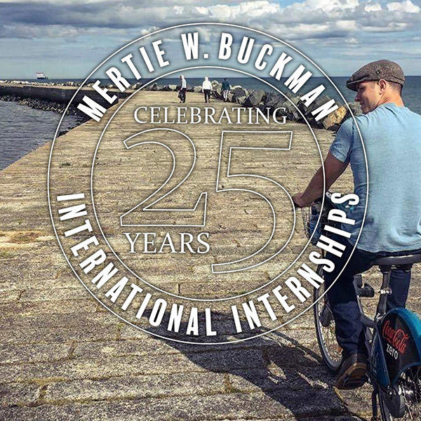 a young man with a hat rides a bicycle on a pier