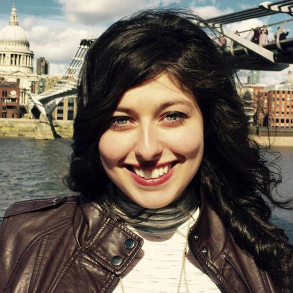 a young woman with dark hair in front of the Thames River in London