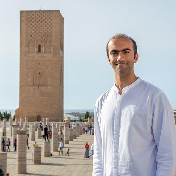 a young man stands in front of a Moroccan tower