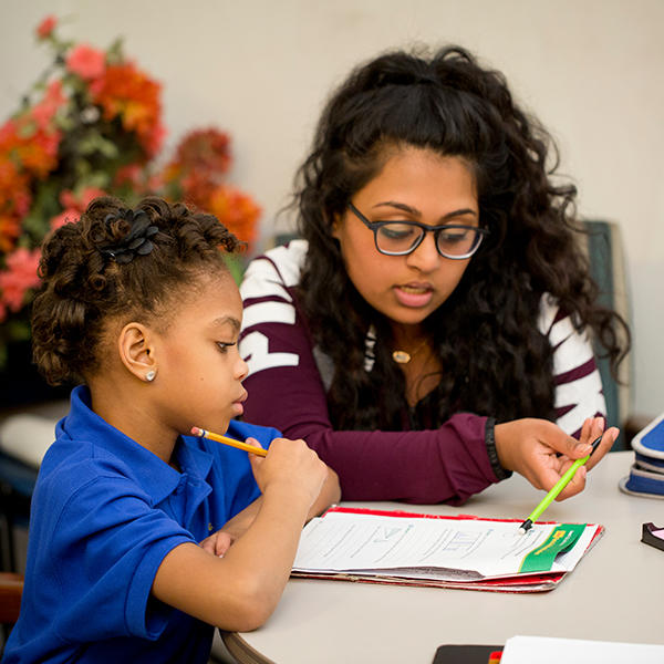 a young woman helps a young girl with her homework