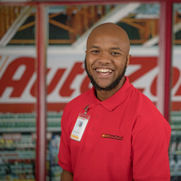 a male standing in front of an AutoZone sign smiles at the camera