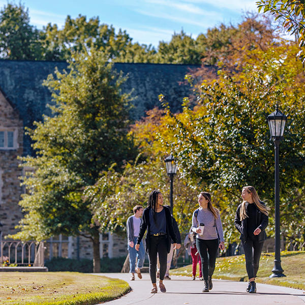 three females chatting with each other walk on campus