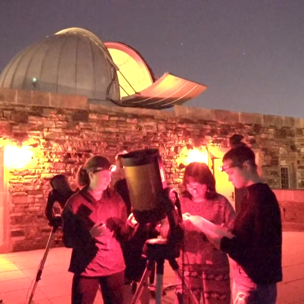 Students on the the astronomy deck gathered around a telescope.