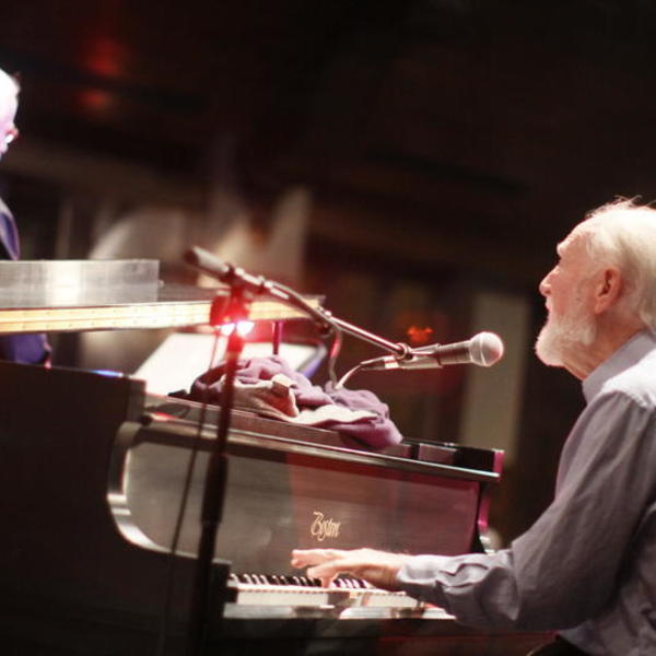 a man with white hair play the piano