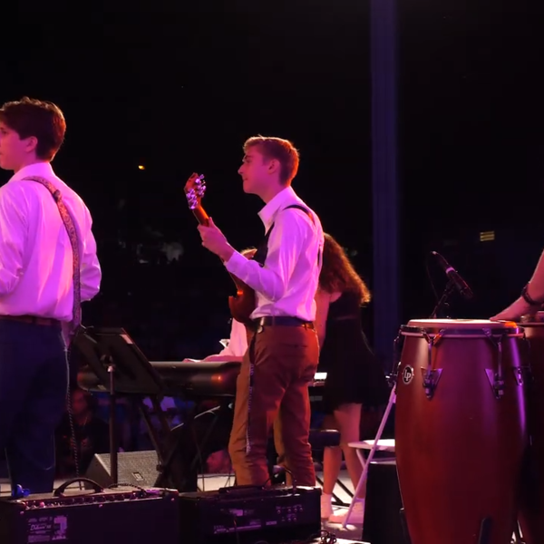 A young man, seen in 1/4 profile, plays the bass on a concert stage.