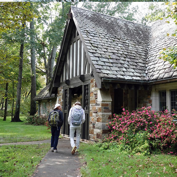 students with backpacks walk to a tudor style building