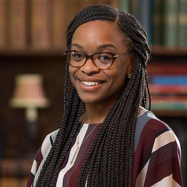 an African American woman with long hair smiles at the camera