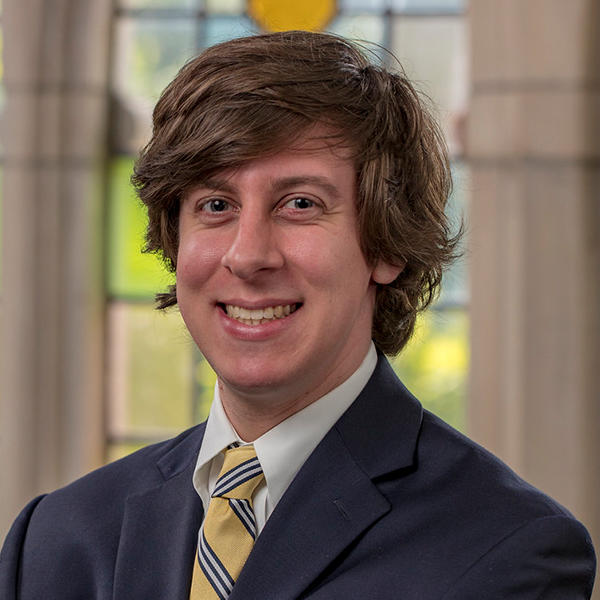 a young man with brown hair in a suit and tie