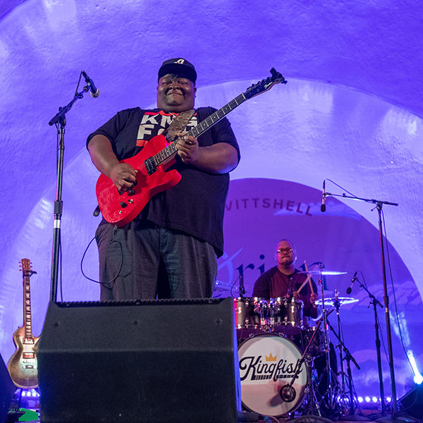 an African American man plays the guitar on a stage