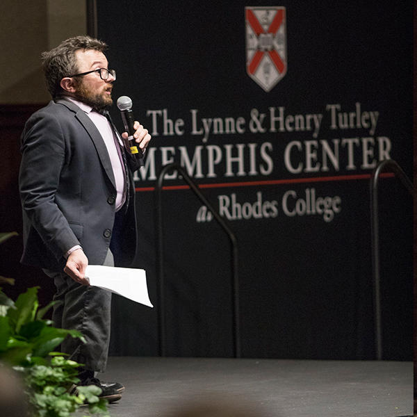 a man speaks on a stage in front of a backdrop for the Memphis Center