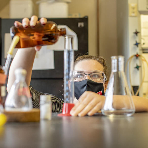 A student carefully measures a red liquid.
