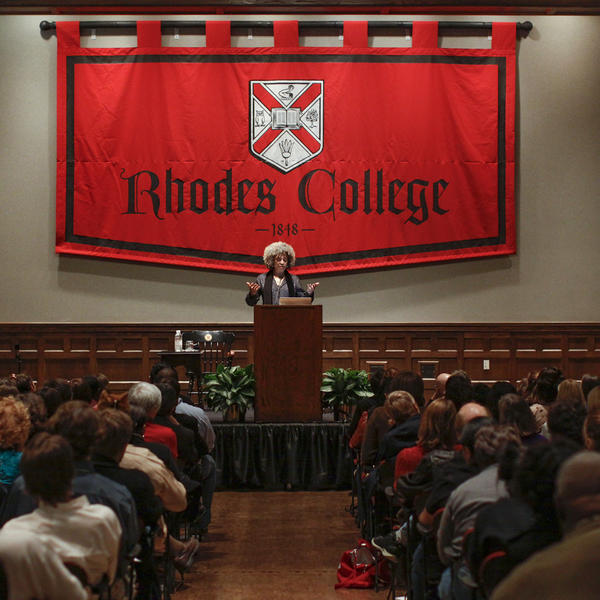 an African American woman speaks in front of a crowded auditorium