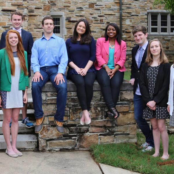 a group of students sit on a stone wall in front of a Gothic building