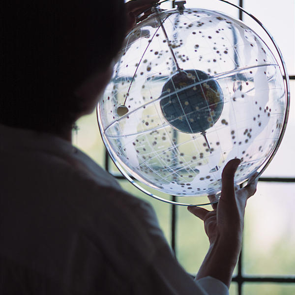 a person holds a model of the earth surrounded by stars on a clear globe