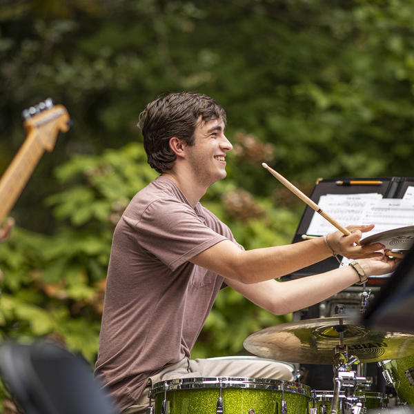a young man at a piano on an outdoor stage