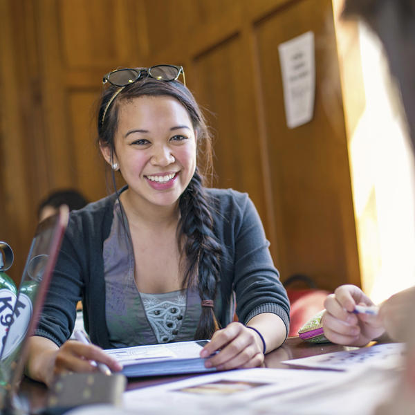 a female student at a table smiles at the camera