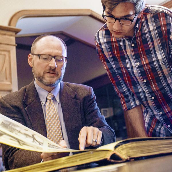 a male professor shows a student a page in a history book