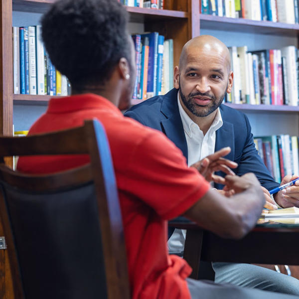 A professor and student sit together talking.