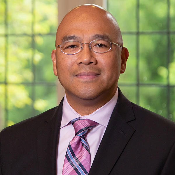  a man with glasses in a suit looks at the camera