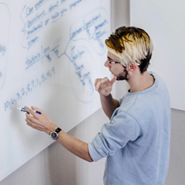 a student works an equation on a whiteboard