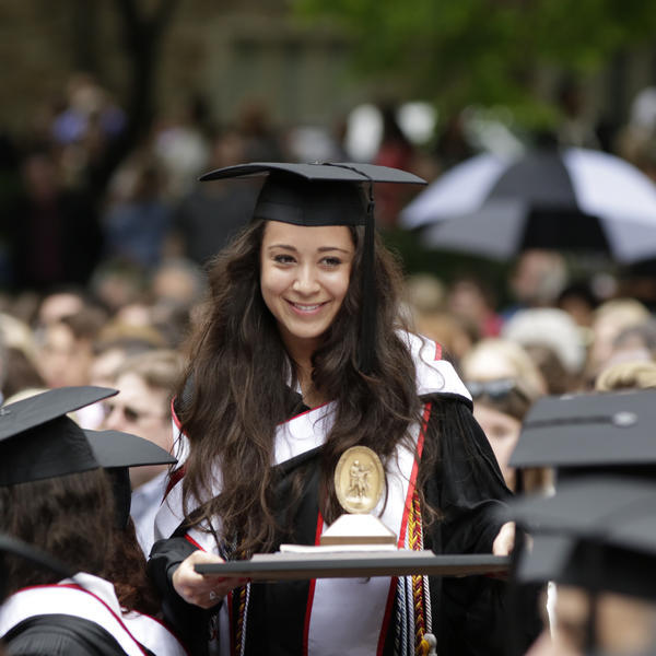 a young woman in academic robes hold her degree