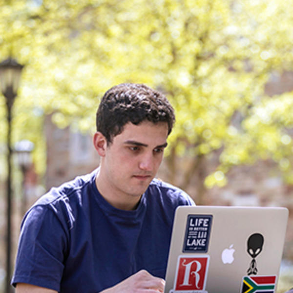 a young man studies a computer outside