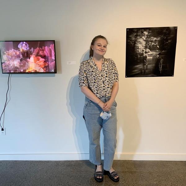 Emily Burkhead, '20, standing in between two of her original pieces of art.