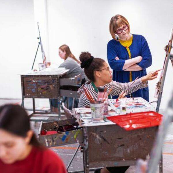 A professor and student discuss a painting in progress.