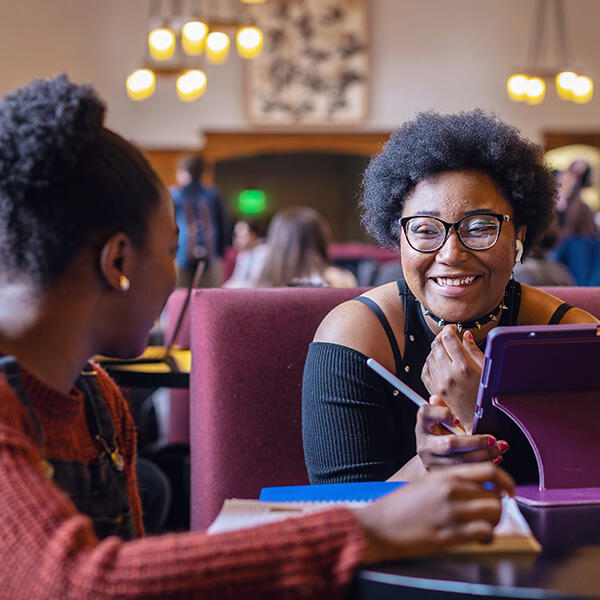 two young African American women work at a table with computers