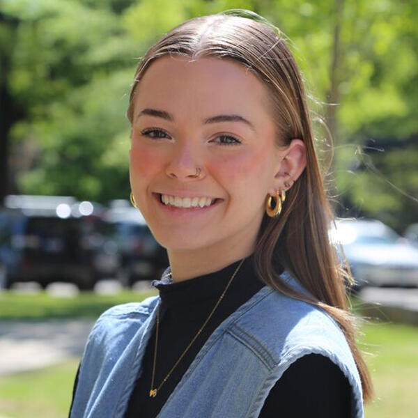 a young woman with brown hair smiles at the camera