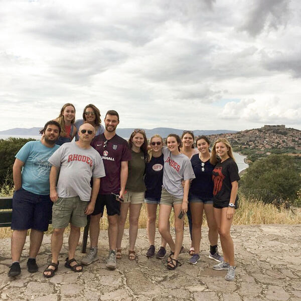 a group of students and a male professor on a hilltop in Greece