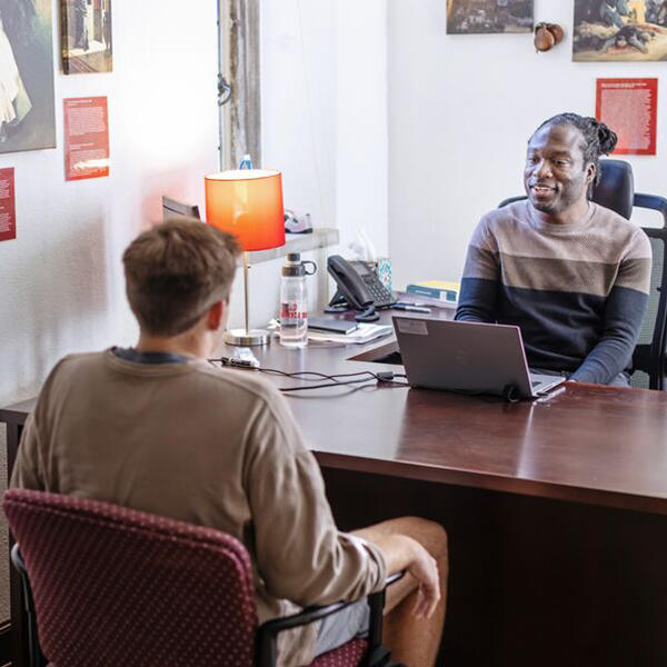 a professor and a student talk in an office