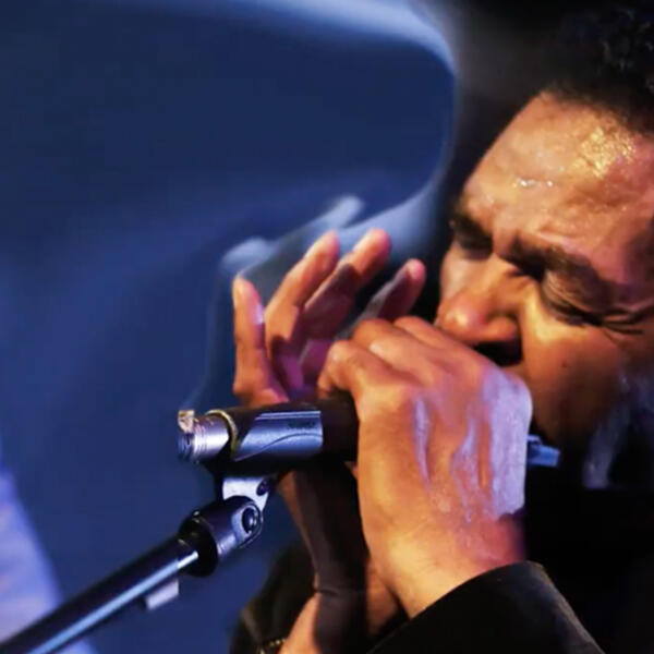 an African American man plays a harmonica