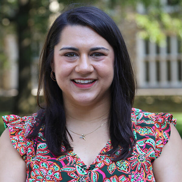 Brooke Mangione, a young woman with long dark hair smiles at the camera
