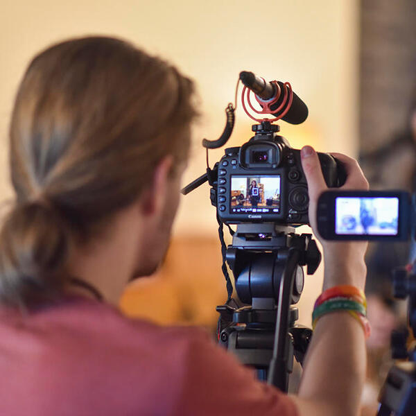 a young man looks through the lens of a video camera