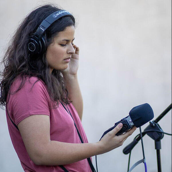 a young woman in headphones holds a microphone