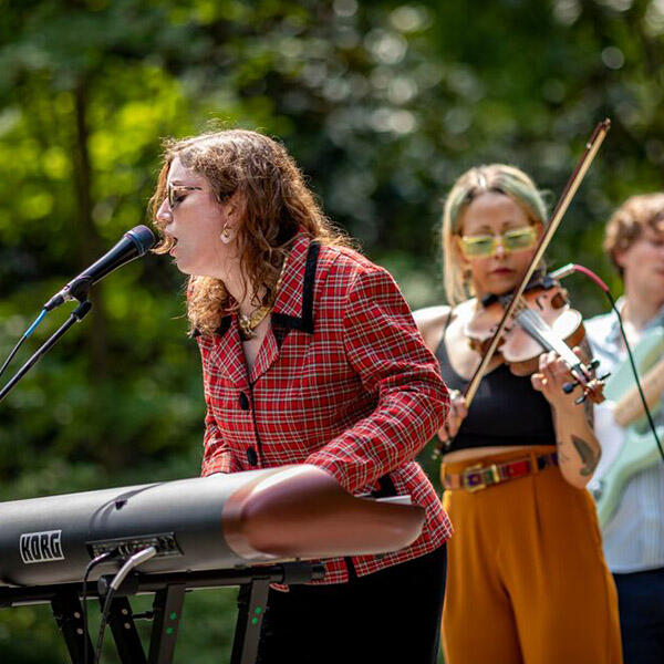 a woman plays the keyboards and another play the fiddle