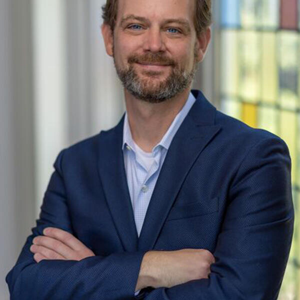 a man with a beard in a blue jacket smiles at the camera