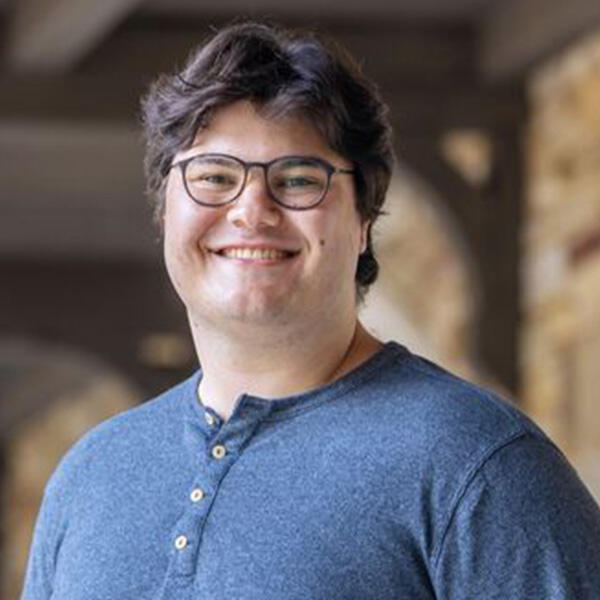 a young man in glasses smiles at the camera