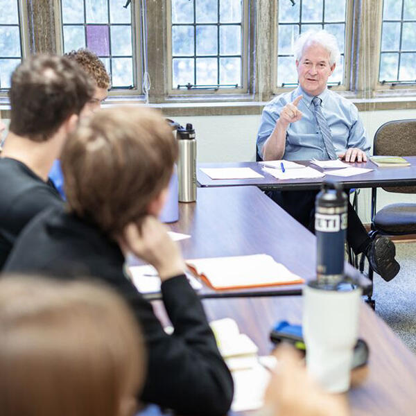 a professor sits at the head of a class