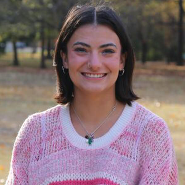 a young woman with dark hair smiles at the camera