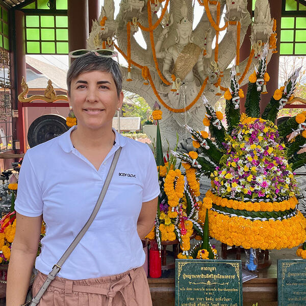 a woman with short hair in front of a statue of a Buddhist god