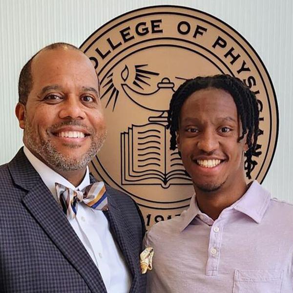 an older man and a younger man in front of a medical seal