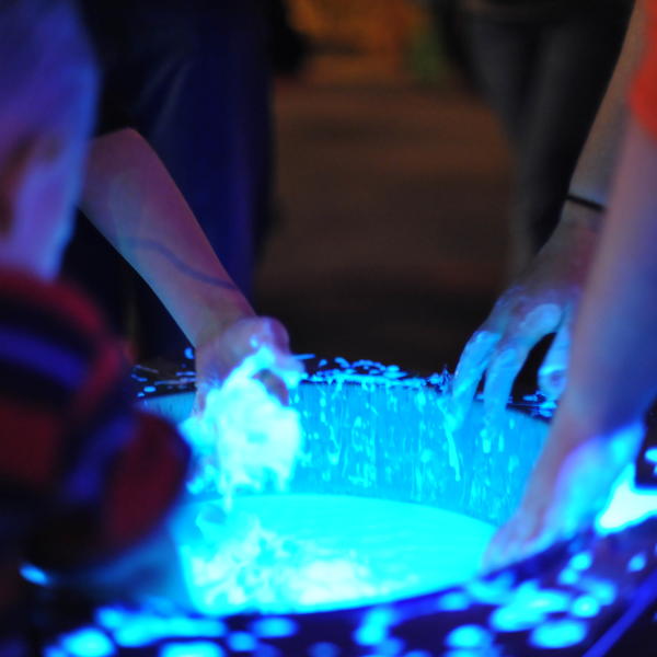 Physics students dip hands in neon blue fluid