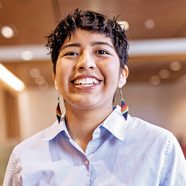 A young woman with short hair and a big smile looks into the camera.