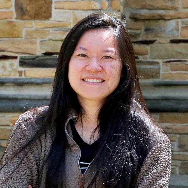 A young woman smiles in front of a sandstone building.