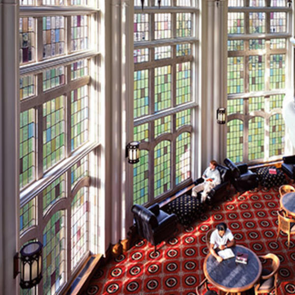 Students sitting in a reading room with two-story stained glass windows.