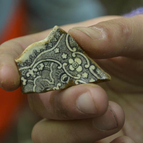 A fragment of a clay pot, intricately decorated with black line drawings.